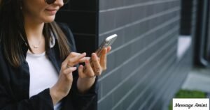 A smiling young East Asian woman with long dark hair looking down at her smartphone, wearing a teal green off-the-shoulder top against a plain white background.