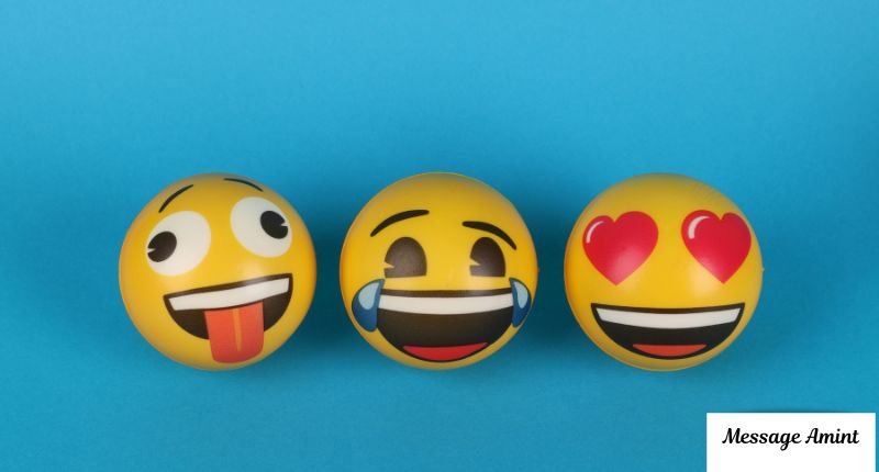 Three yellow emoji stress balls lined up side by side against a solid blue background, showing a tongue-out face, a crying-laughing face, and a heart-eyes face from left to right.